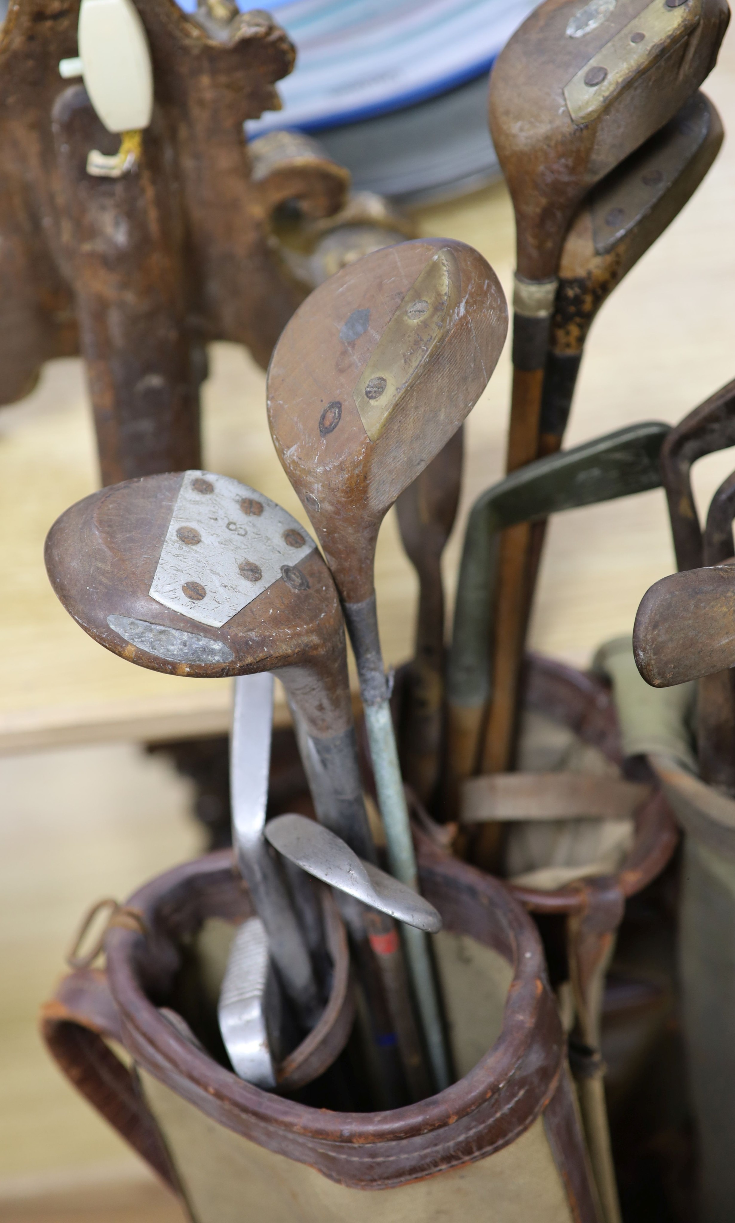 A collection of pre-war golfing irons and woods, contained within three canvas golf bags